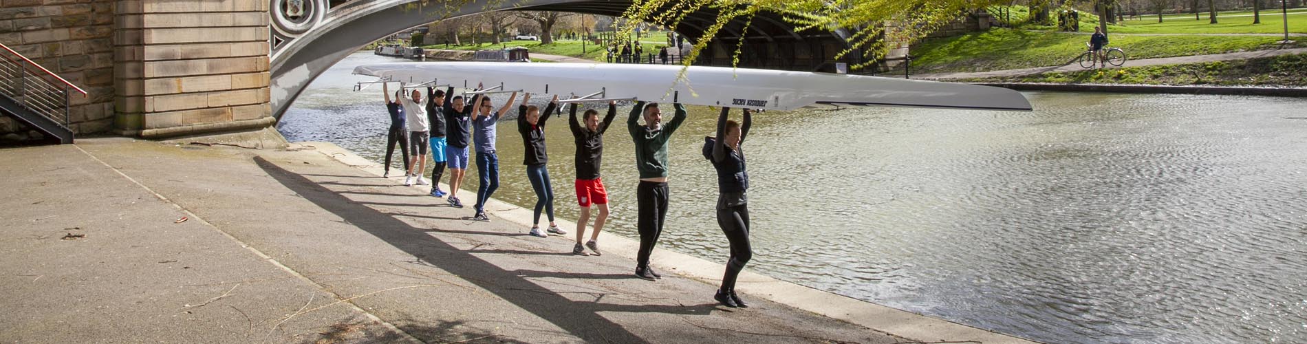 Group of people carrying an upturned boat by the River Cam