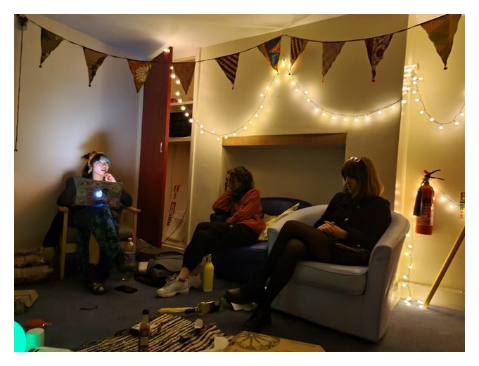 Three friends sat in a room with bunting and fairy lights
