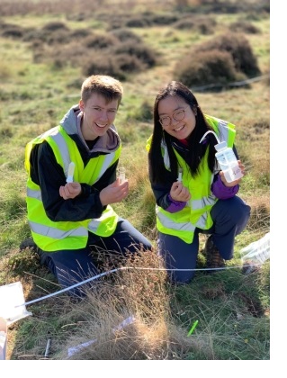 Belinda and another Geography student posing with equipment in a field whilst gathering data during a practical session.