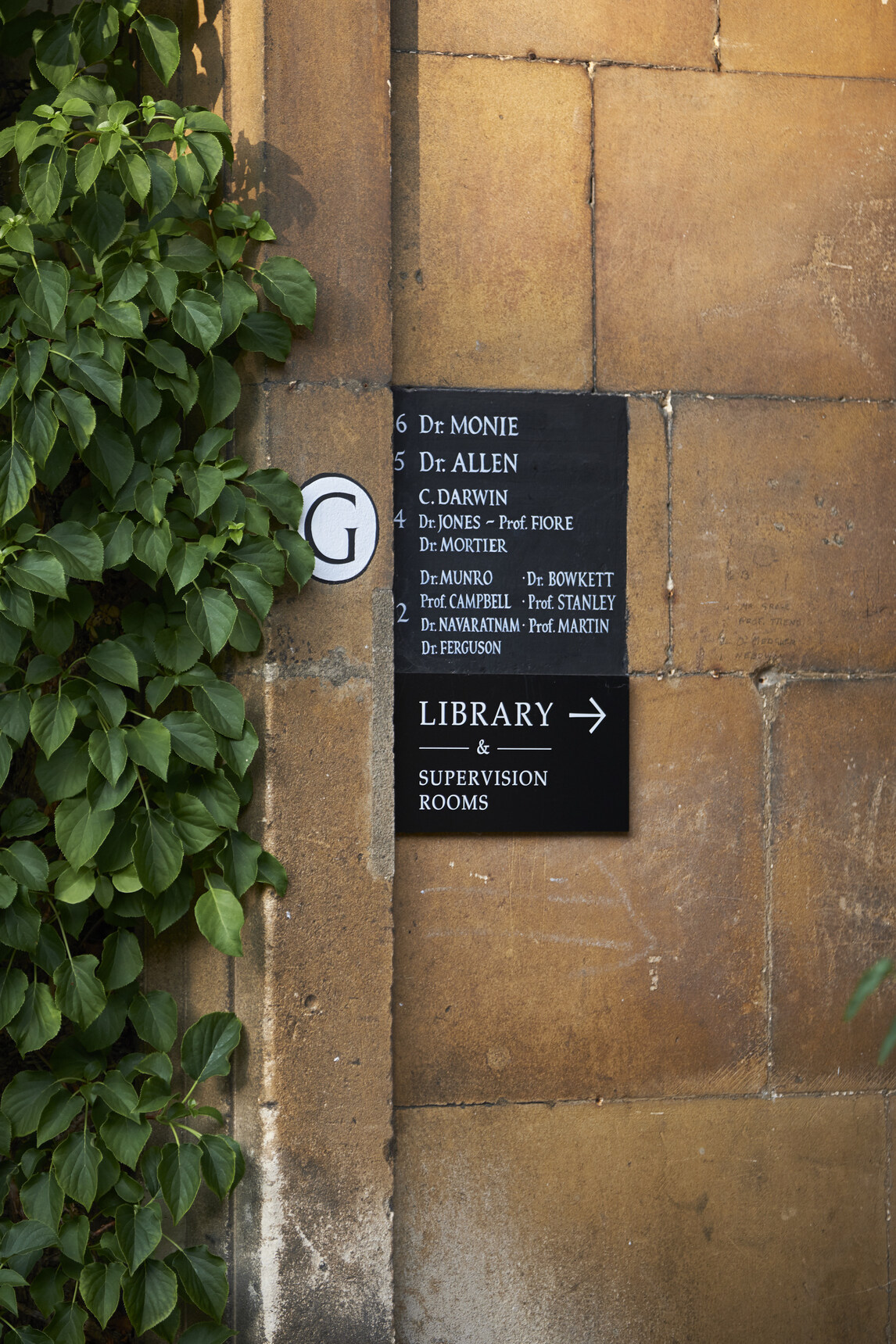 Sign showing rooms in G staircase, including C Darwin. 