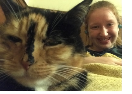 A selfie featuring a young woman and a cat, who is squinting suspiciously at the camera.