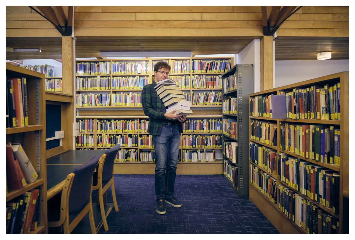 Student with a pile of books in the library