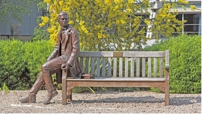 A statue of a young Charles Darwin sitting on a bench in New Court of Christ's College, Cambridge.