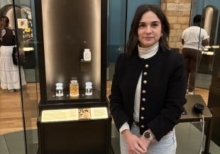 Marina beside a display case with three jars containing worms and a white medicine container