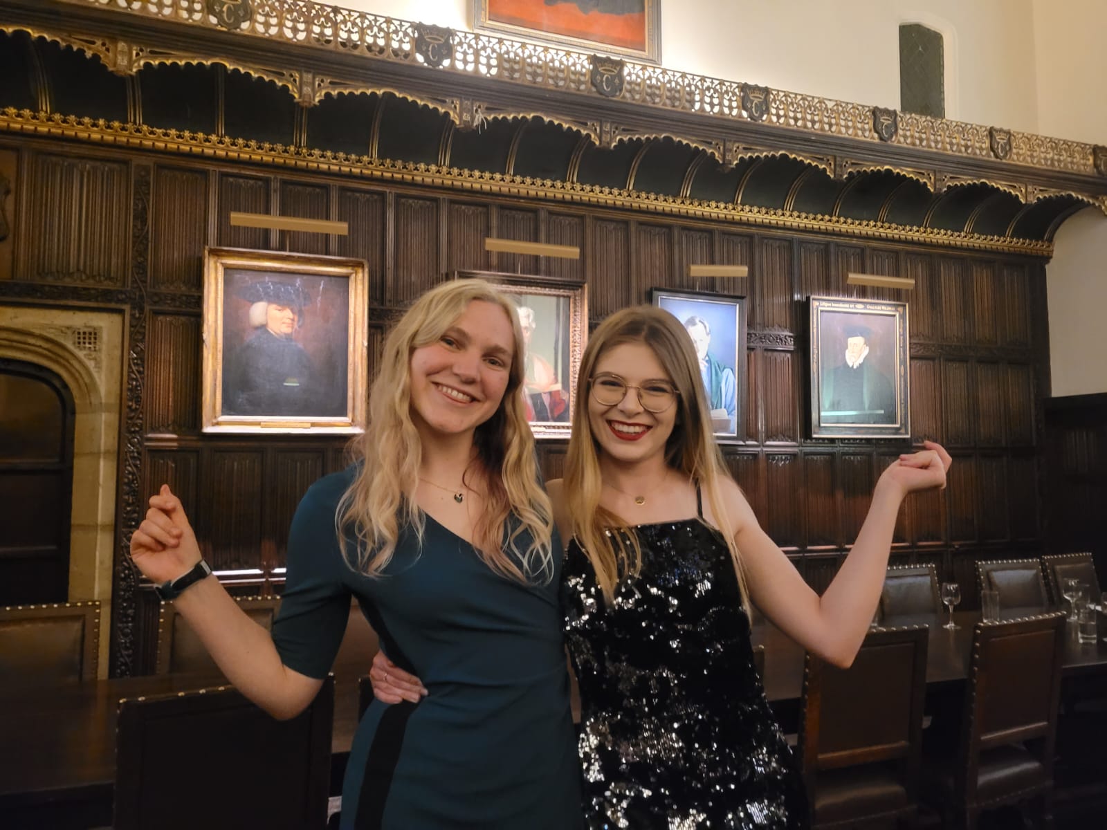 Two students doing a sassy pose, laughing, in Formal Hall