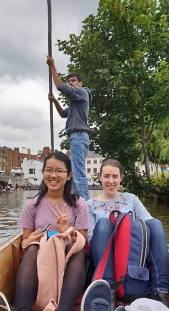Two friends smiling on a punt (boat driven by a person with a pole)