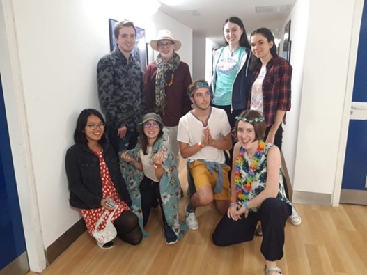 A group of 8 friends in 'gap yah' outfits posing in a hallway