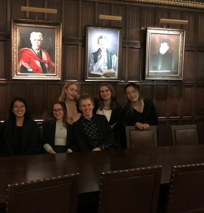 six friends stood in front of a wall with some portraits on in Christ's formal dining hall