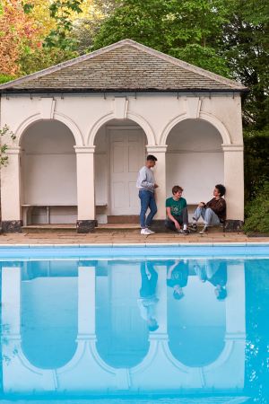 Eebbaa and friends sat in the porch of the poolhouse, in front of the outdoor pool at Christ's College, Cambridge.