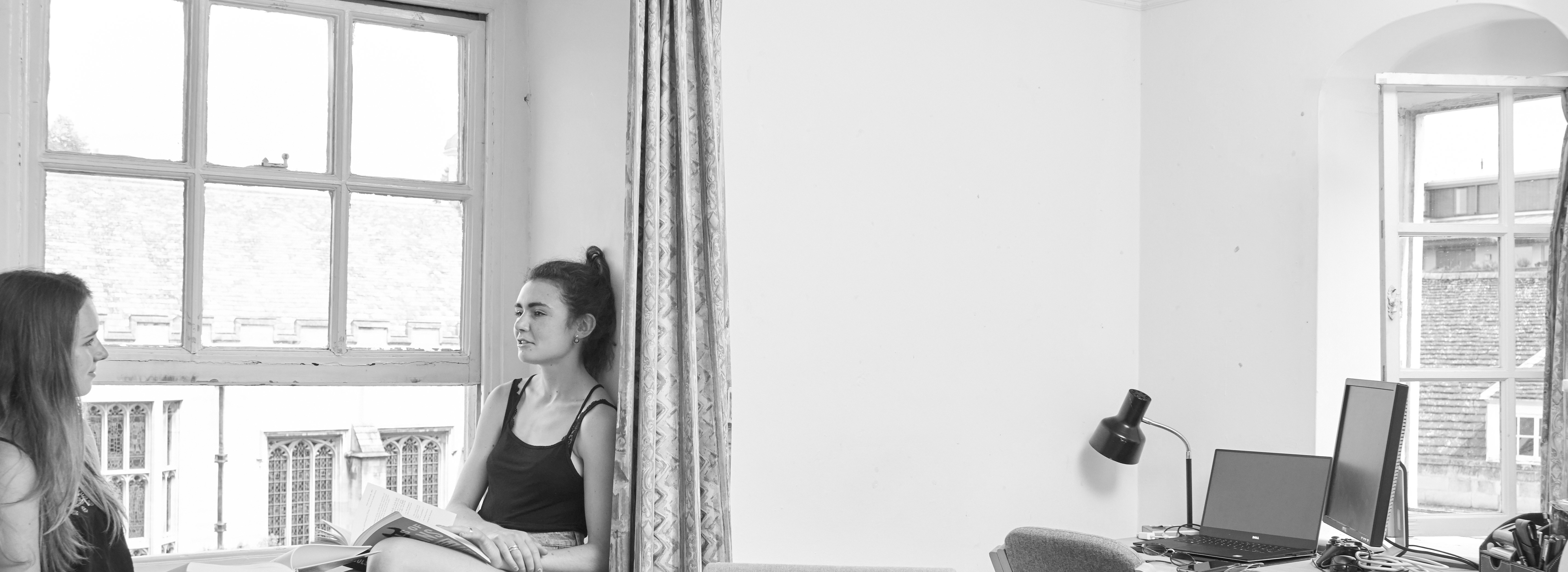 Two students talking, sat in the window