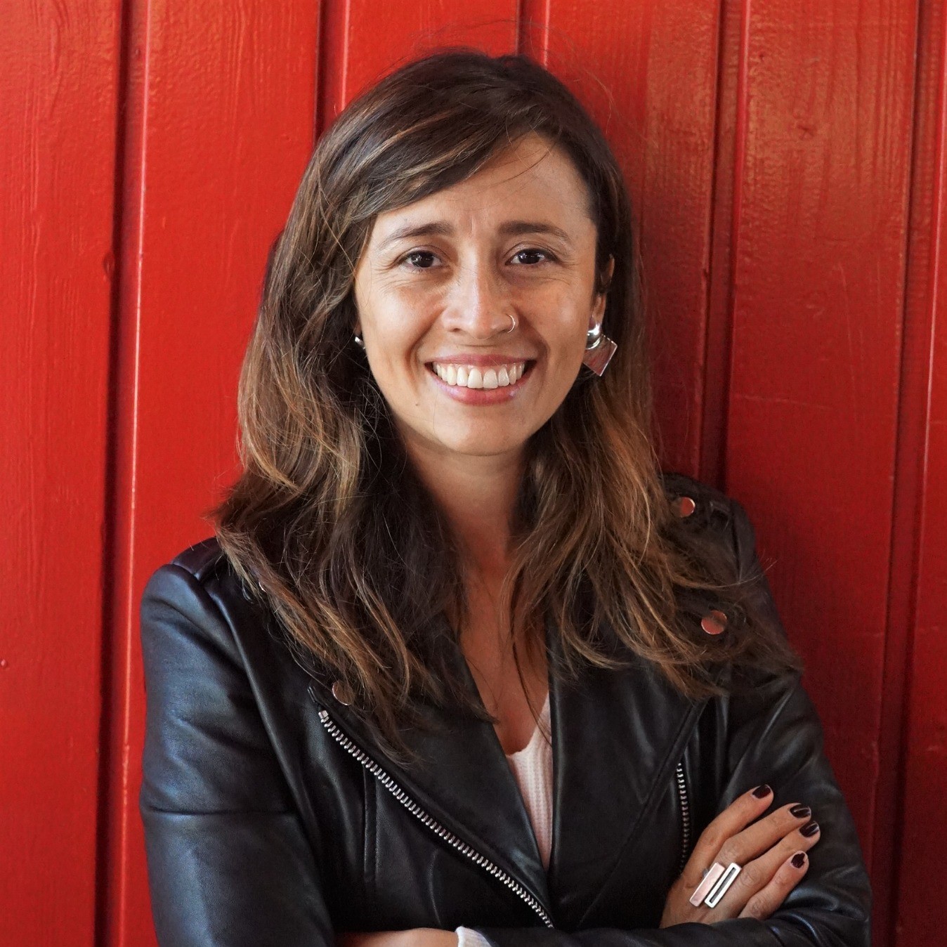 Smiling person in leather jacket with folded arms