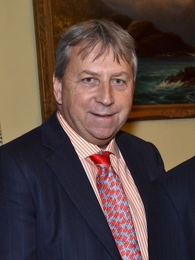 Peter Mathieson smiling, wearing suit, shirt and tie