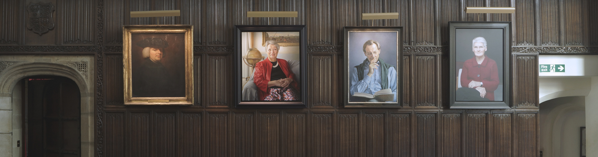 Four portraits hanging on a wood panelled wall