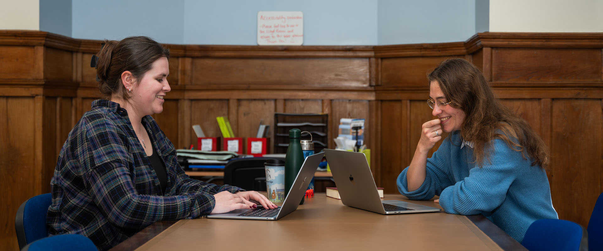 Two smiling students working on lap tops