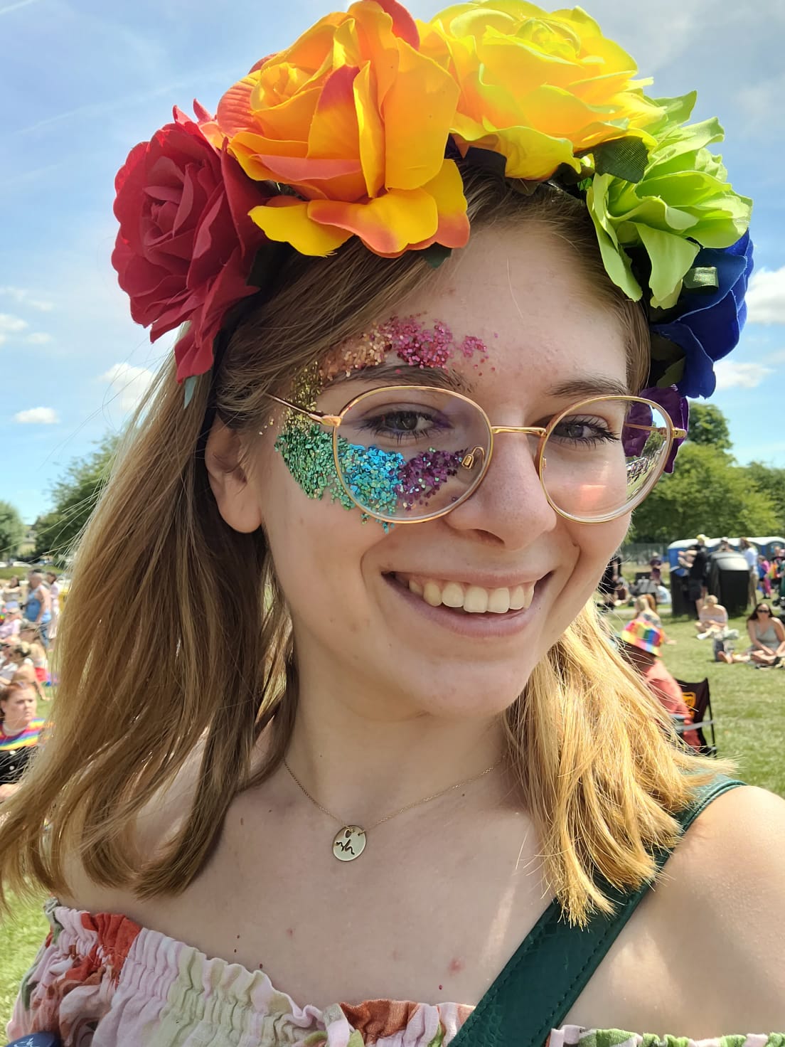 Selfie of Oliwia, with a rainbow flower headband and rainbow glitter on her face