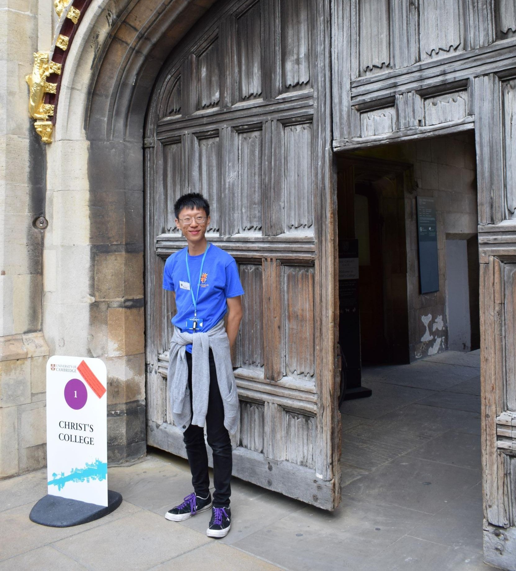 Student at main gate with the College sign for an open day