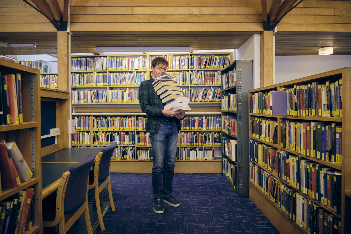 Student with pile of books in the library