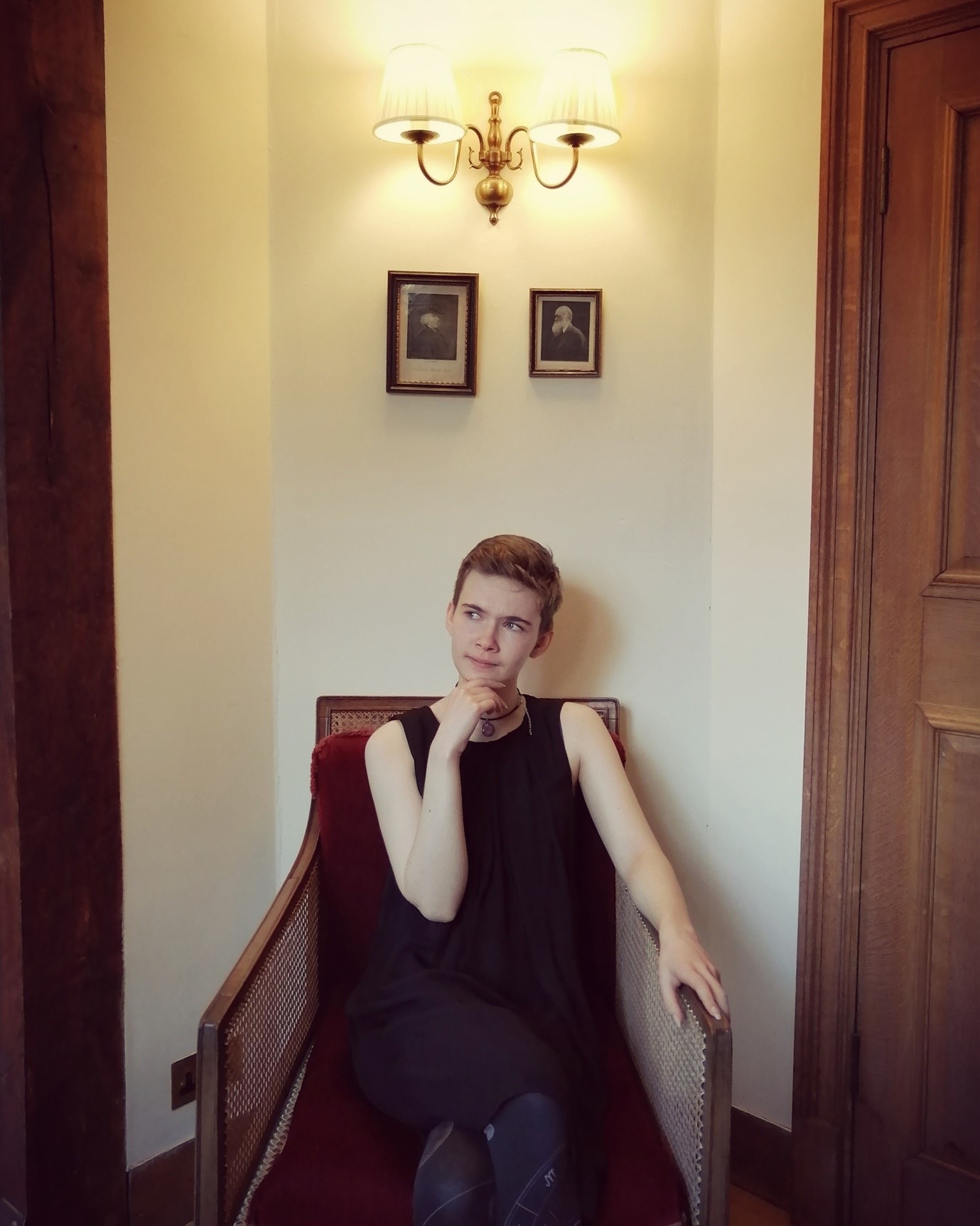 Ariel, a young white woman with short hair, sat looking thoughtful on a chair