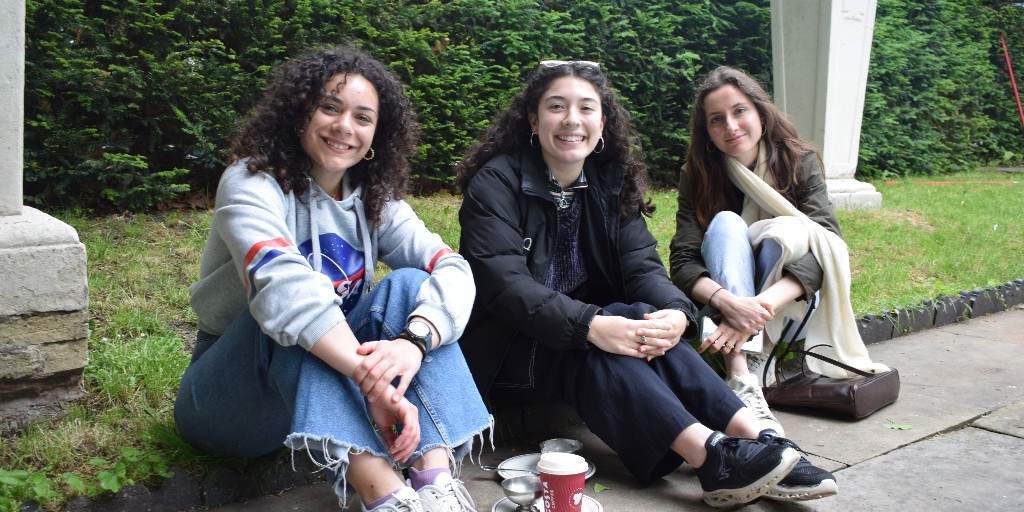 Three students sitting on grass