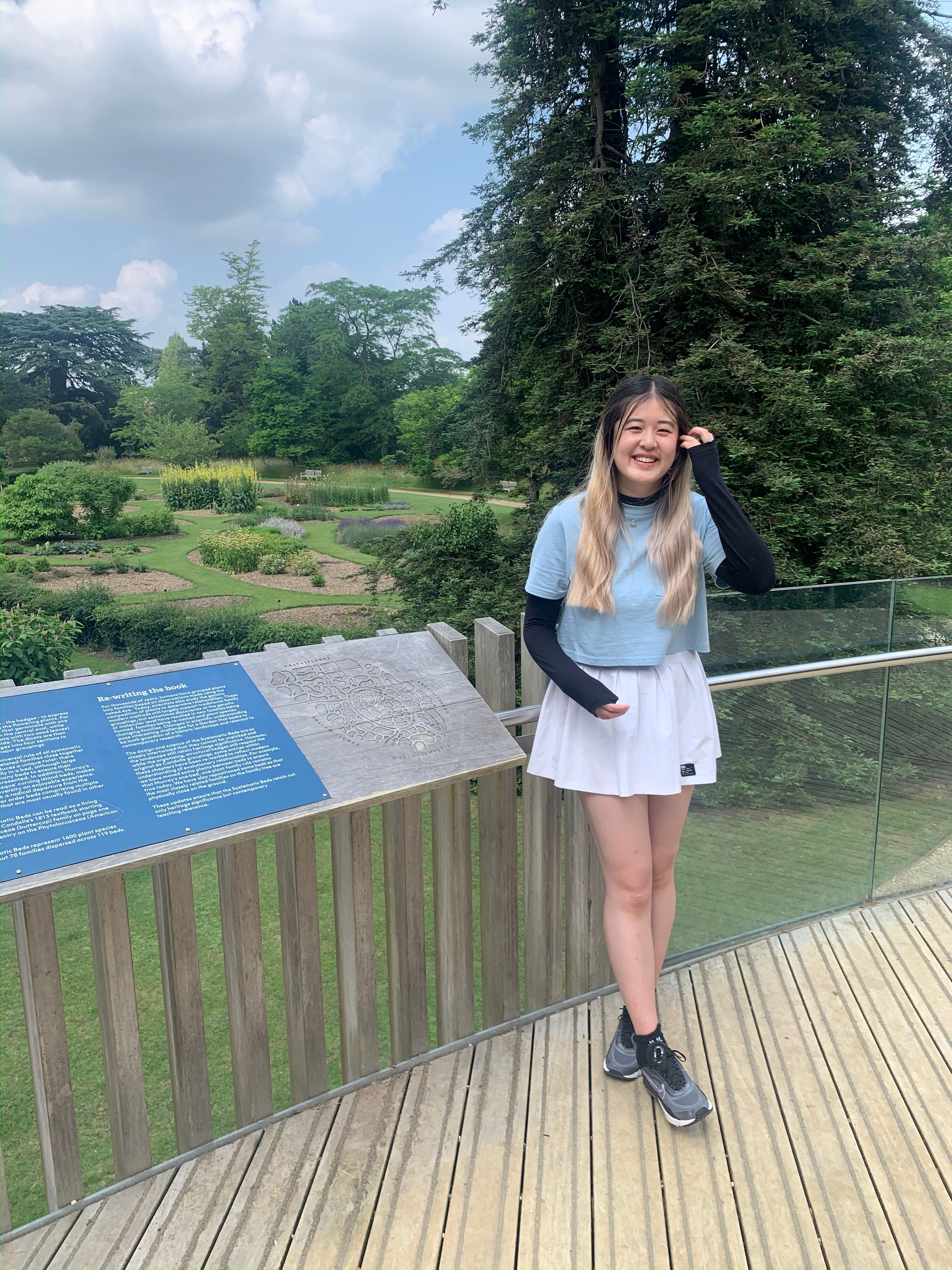 Hannah in front of a sign and a well-kept garden