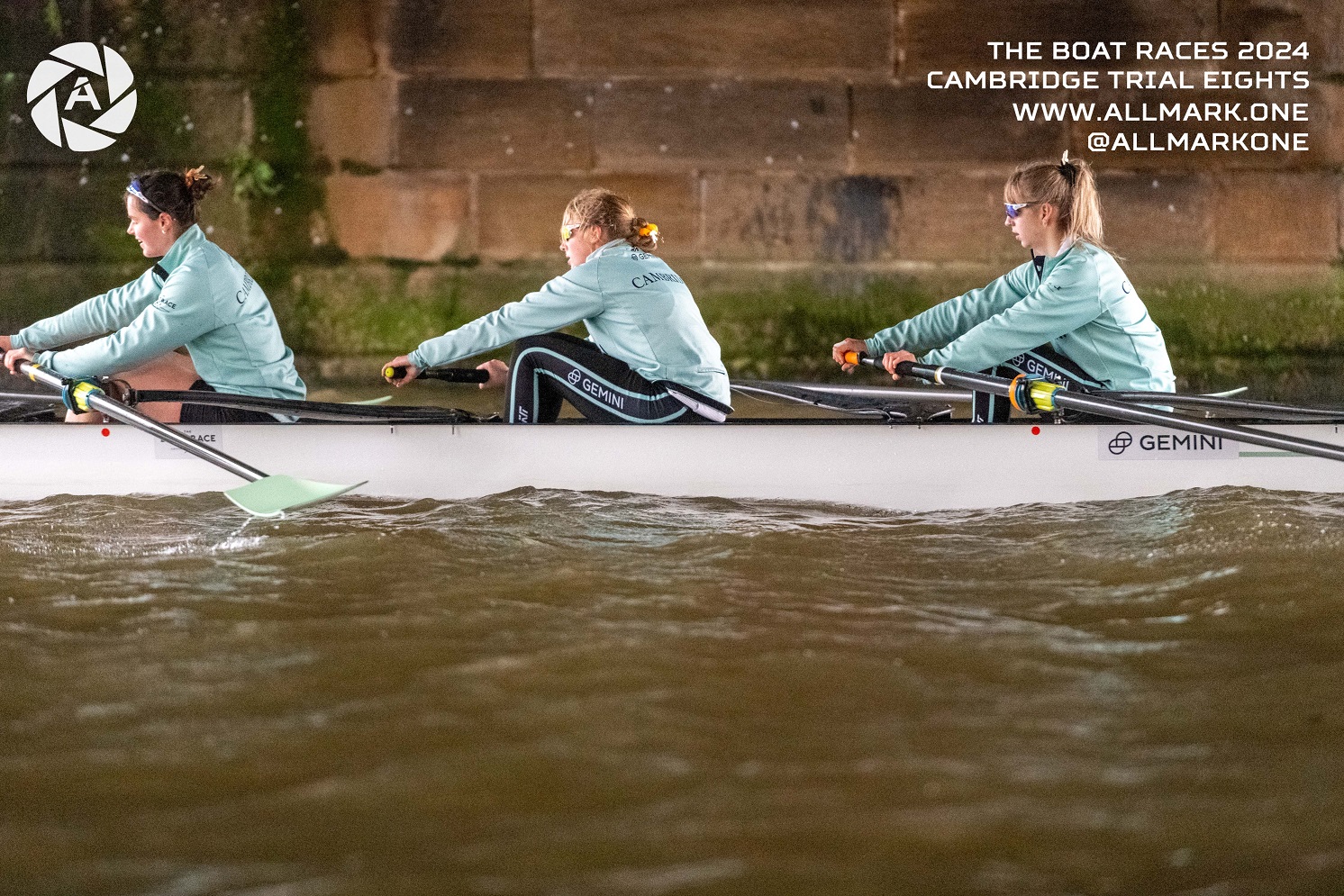 Three rowers in a boat under a bridge