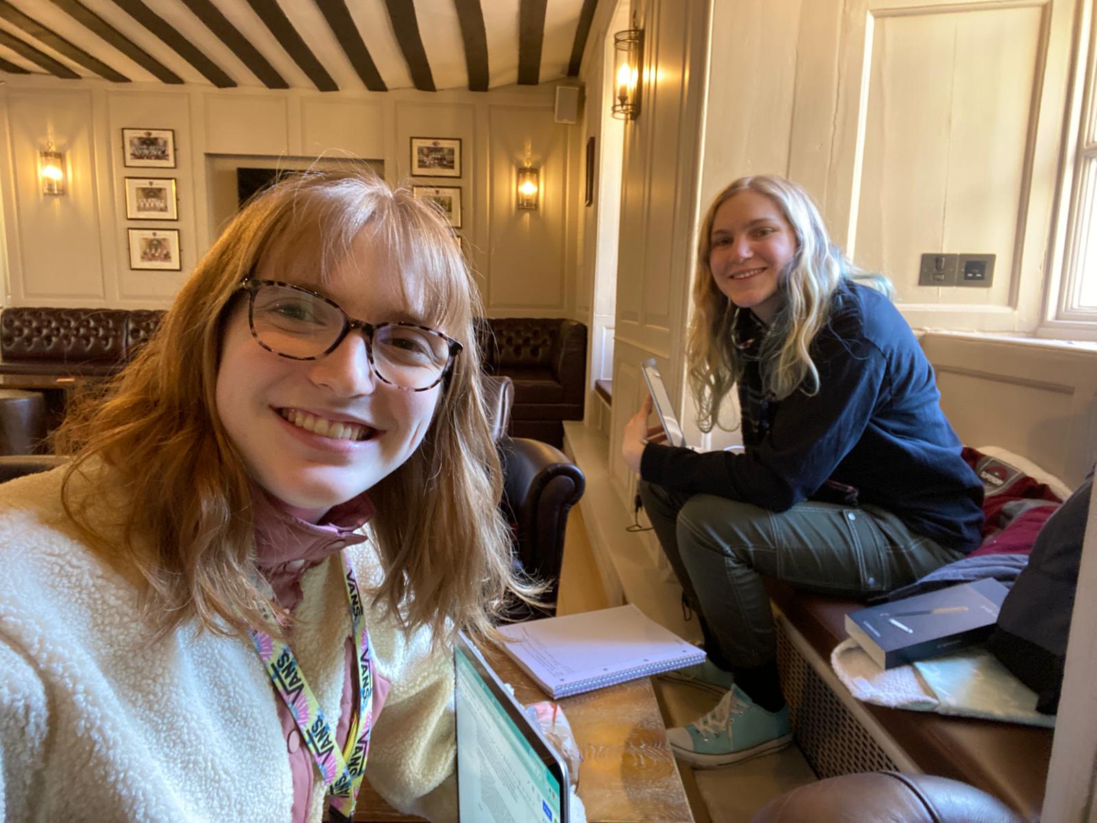 A selfie of two students with laptops in the Buttery