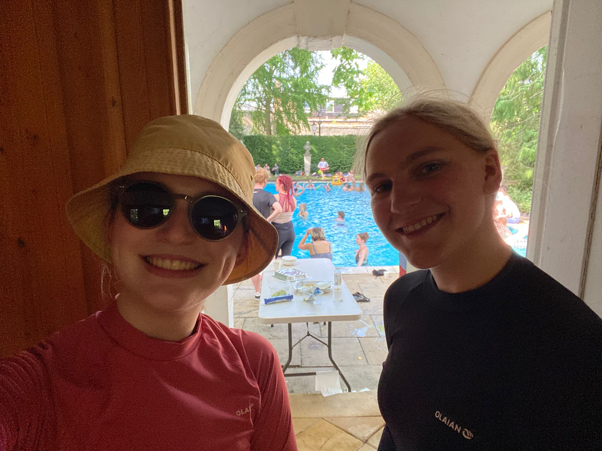 Two students in swimming shirts, in front of the pool