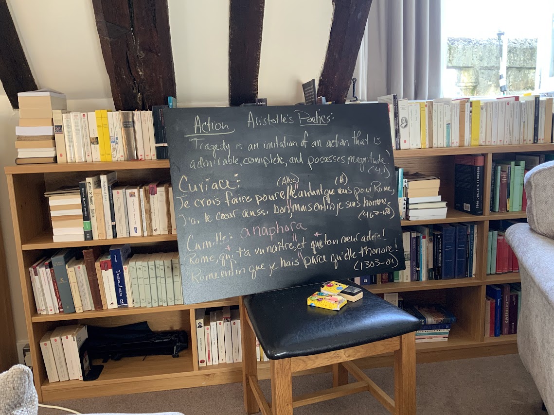 A chalkboard on a chair, in front of a big bookshelf