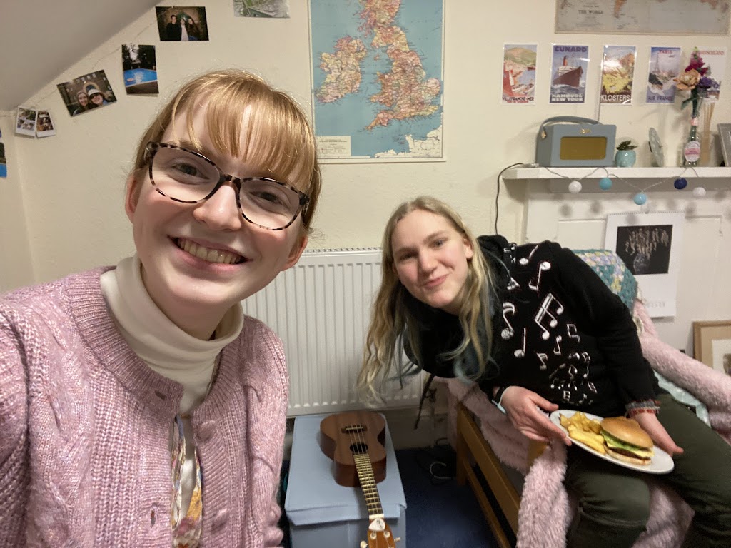 Two students in a room with posters and photos in the background