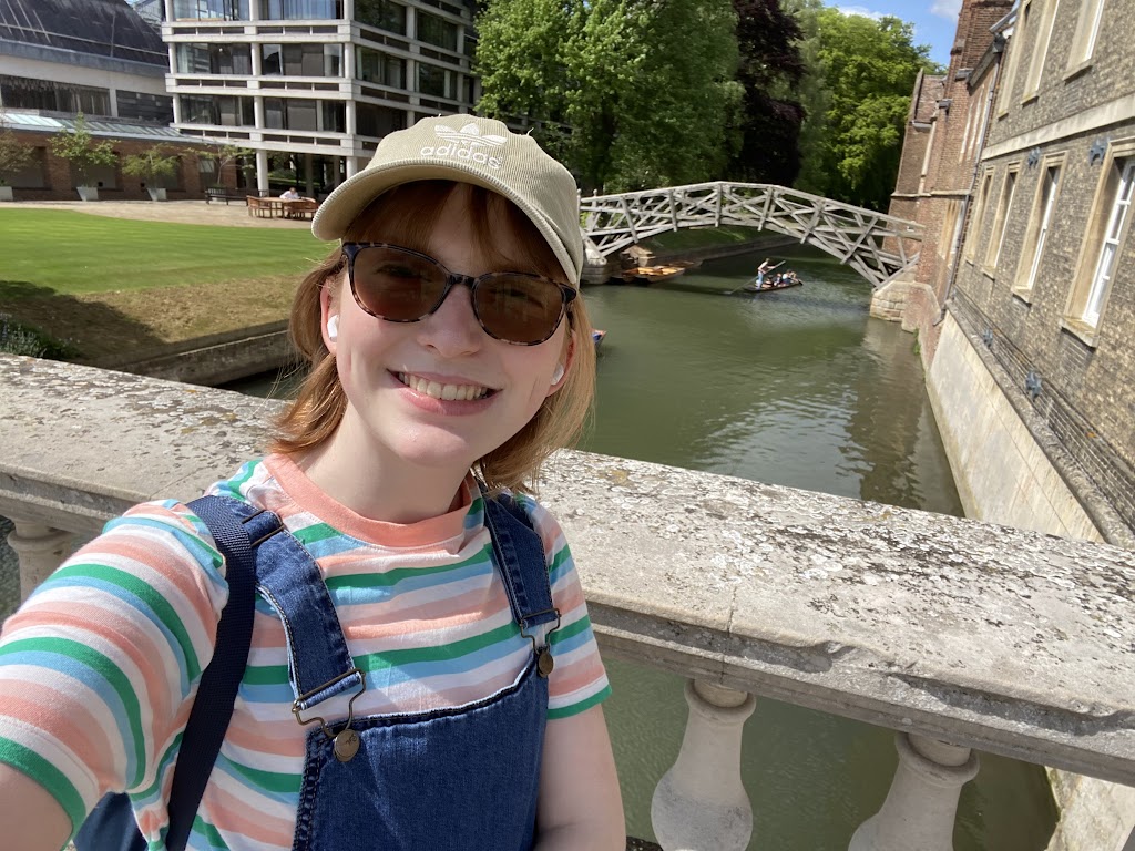 A selfie of a student on a bridge, with the Mathematical Bridge in the background