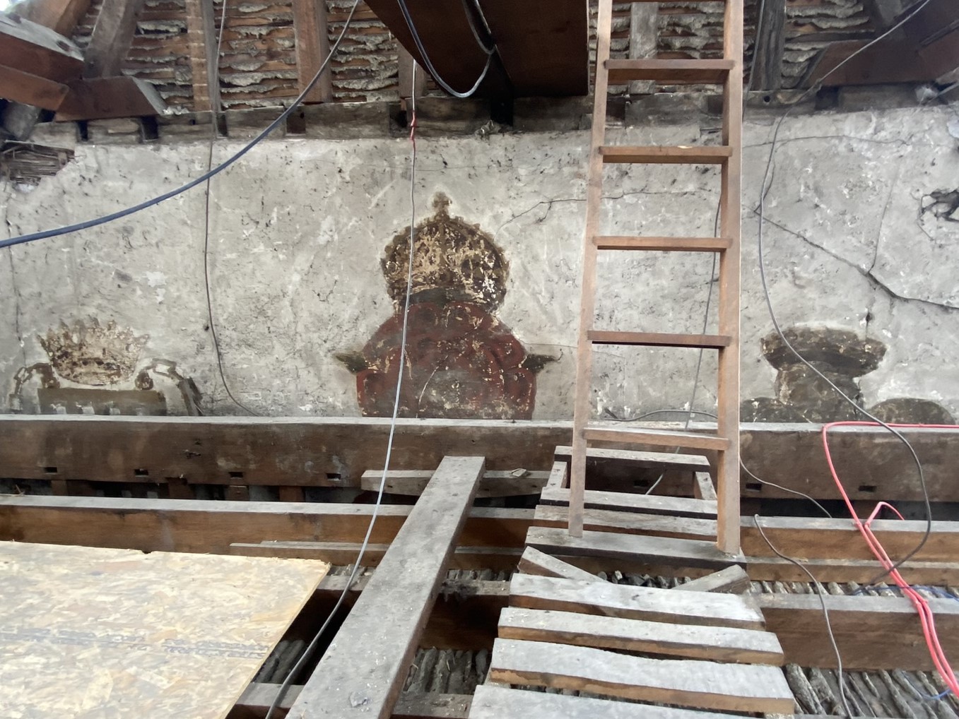 Wall paintings in a loft space with a ladder in the foreground