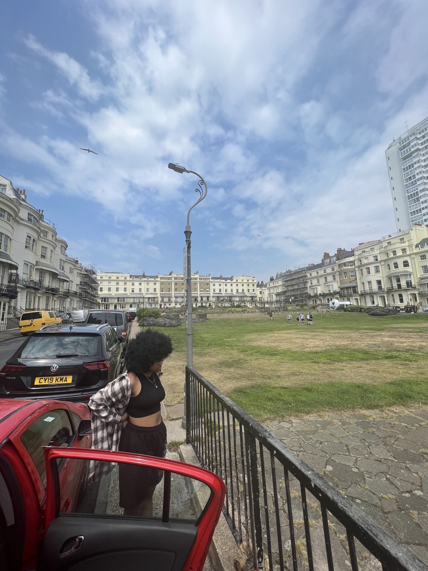 Eri stood next to a car, with a park in the background