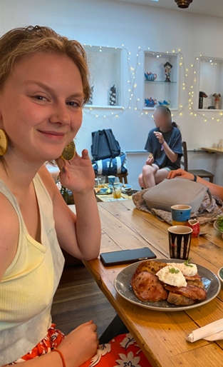 Student with a plate of breakfast, smiling at the camera