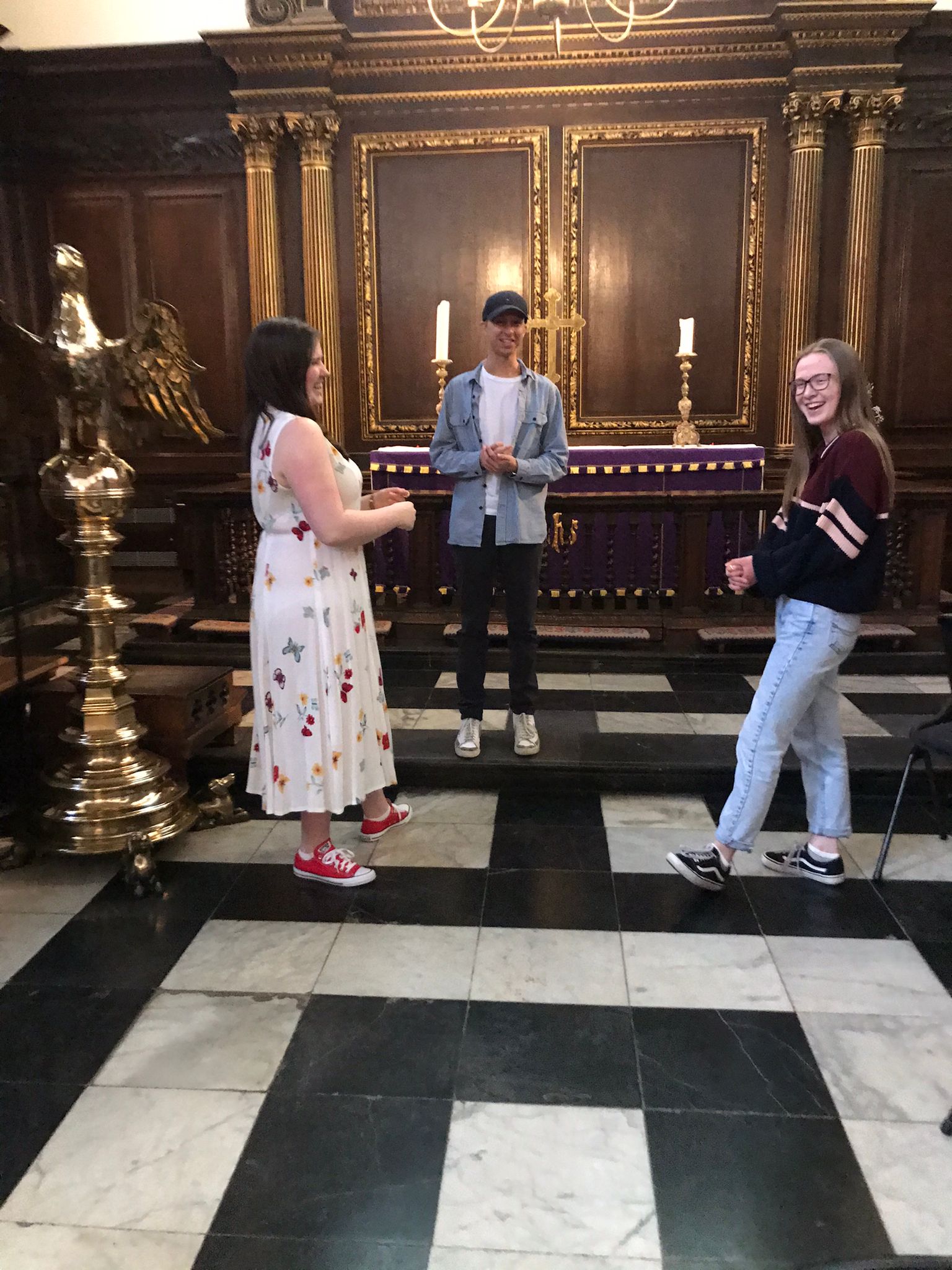 Two women facing each other in the college chapel, laughing. 