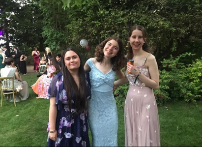 A group of three students in a garden, wearing formal dress
