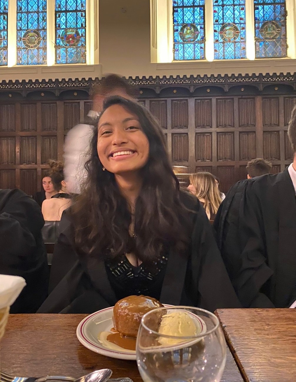 A student in a gown, with a dessert in front of them