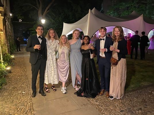 Seven friends in formal dress, in front of a marquee in the dark