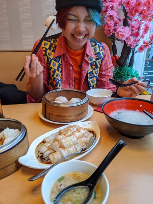 A student at a table of food, holding chopsticks