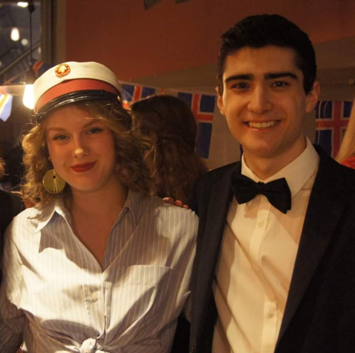 Two students in formal dress, one with a danish graduation hat