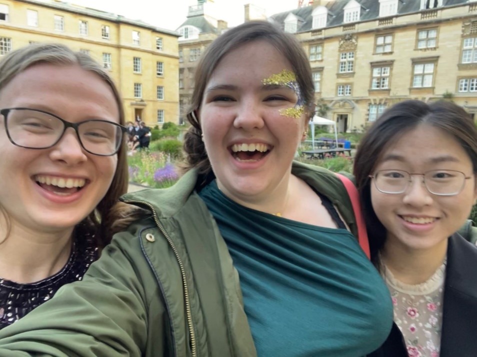 Three students in a selfie, with third court in the background. Annie has glitter on her face