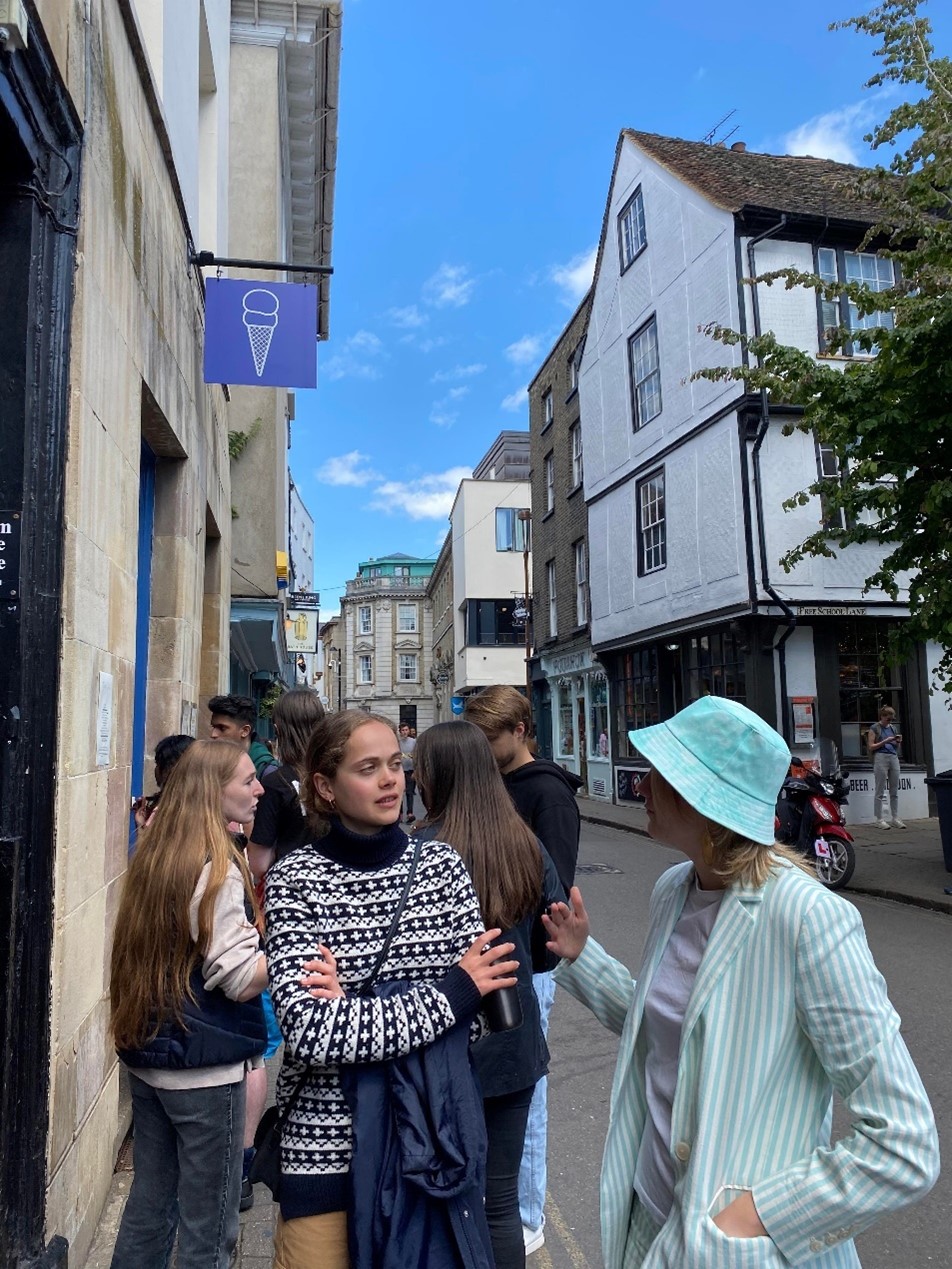 Students waiting in a queue, with an ice-cream sign above their head