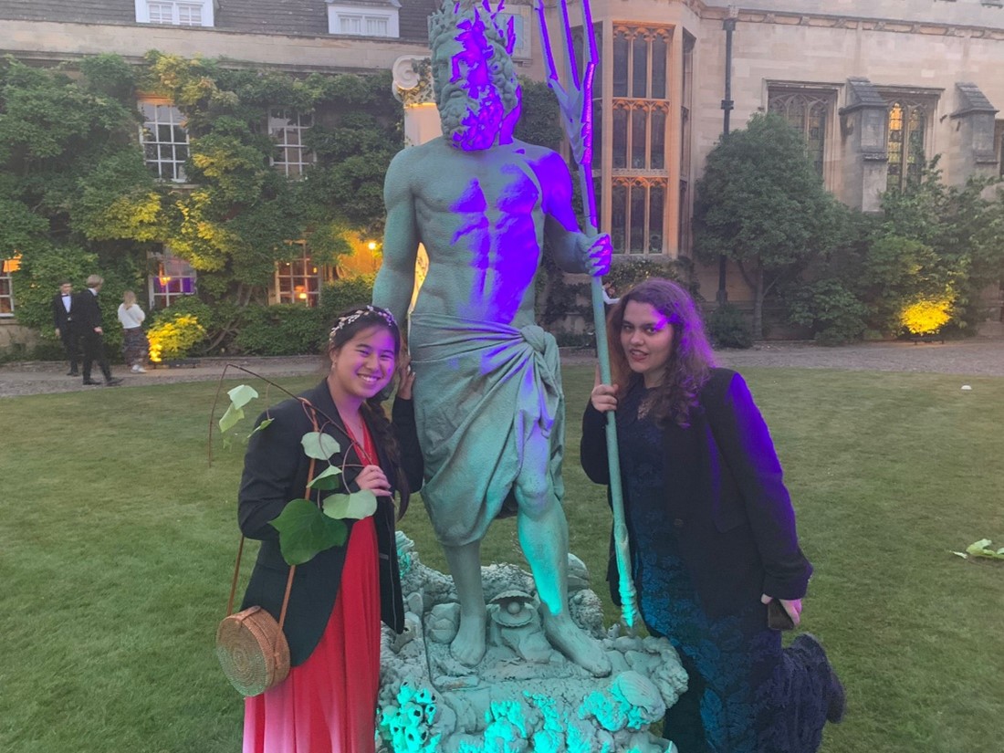 Two students with a greek-style statue