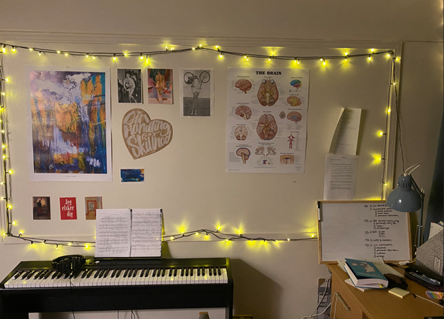 A keyboard, with some fairly lights and photos on the wall above