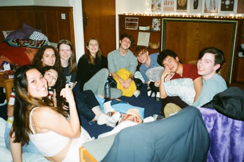 A poloroid-style group of friends, sat on the floor in a student room