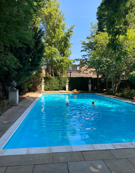 Outdoor swimming pool, with a few people in it. 