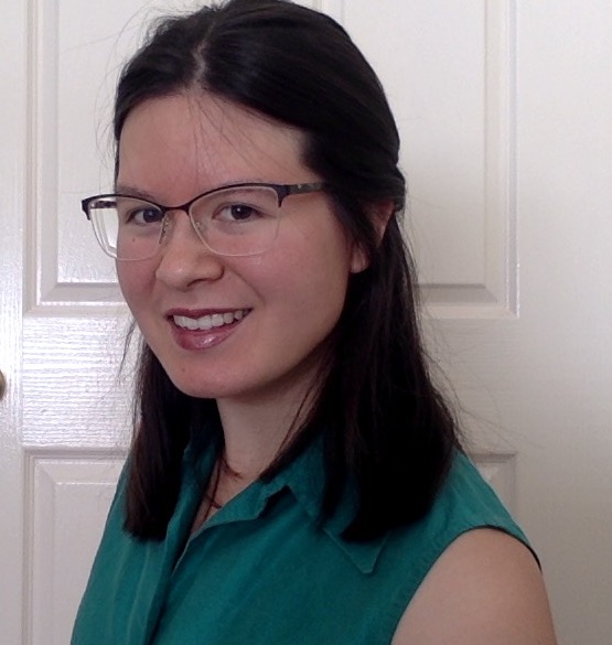 A headshot of a person with long dark hair and glasses