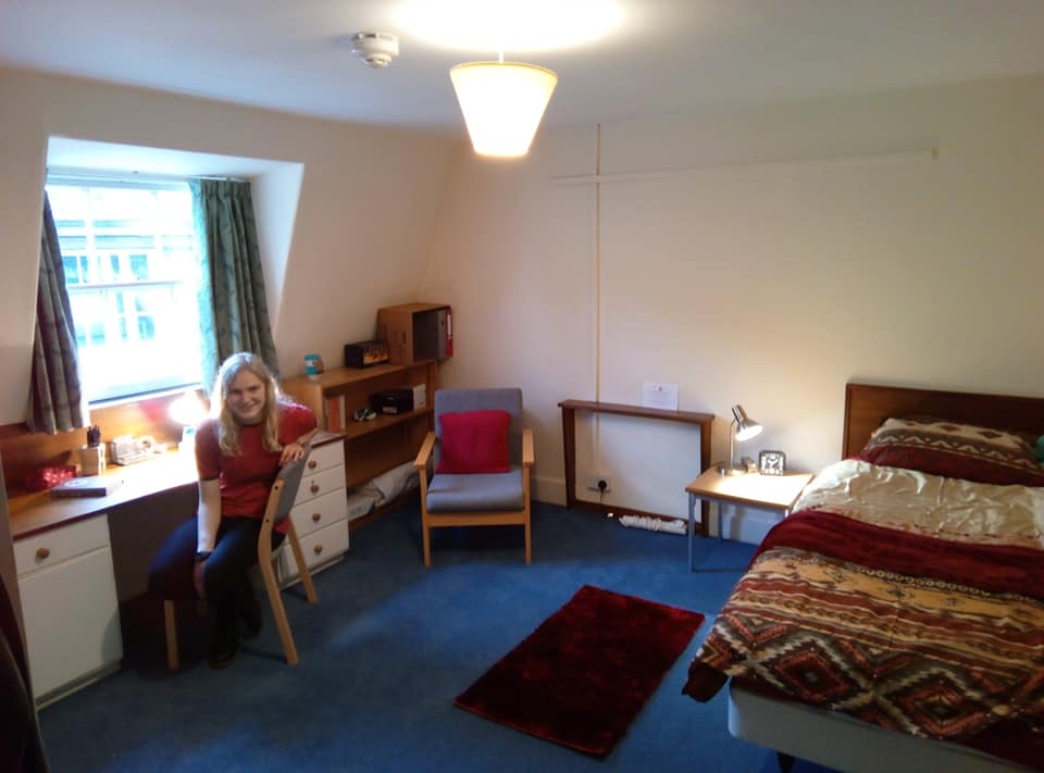 A student sat at a desk in a room with a blue carpet and red decorations