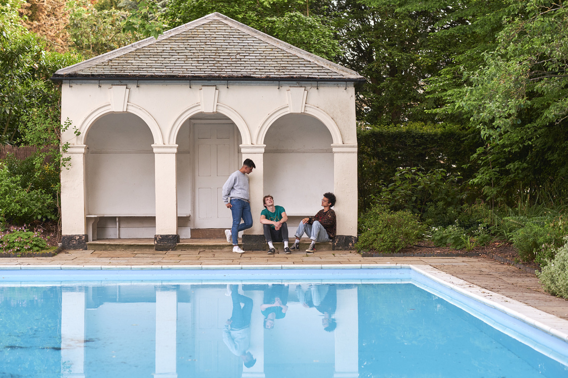 Swimming pool with three students chatting in the background