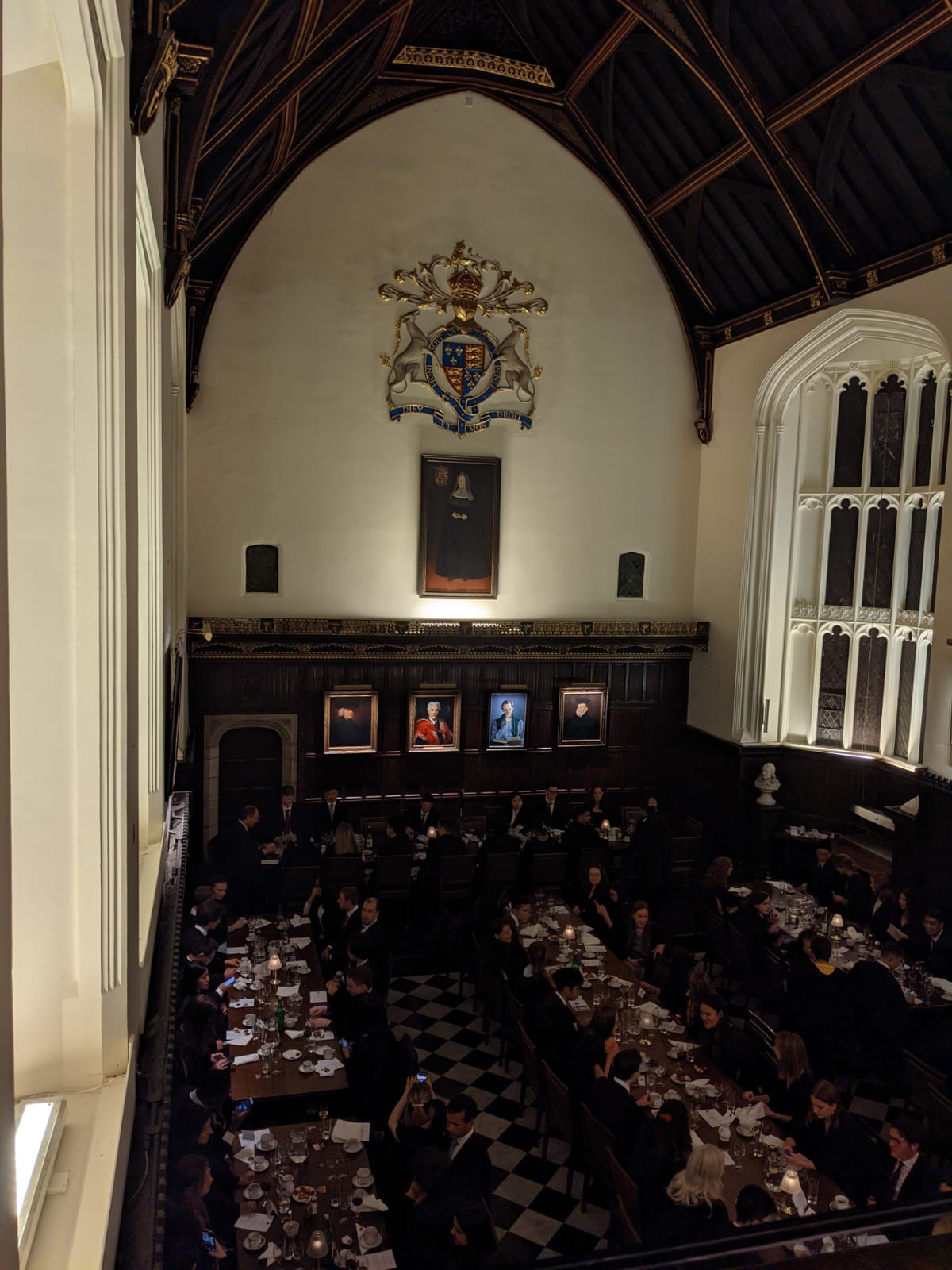 View of formal hall from the balcony: students in formal clothes sat at long tables.