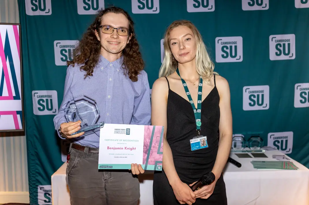 Two people, one holding an award